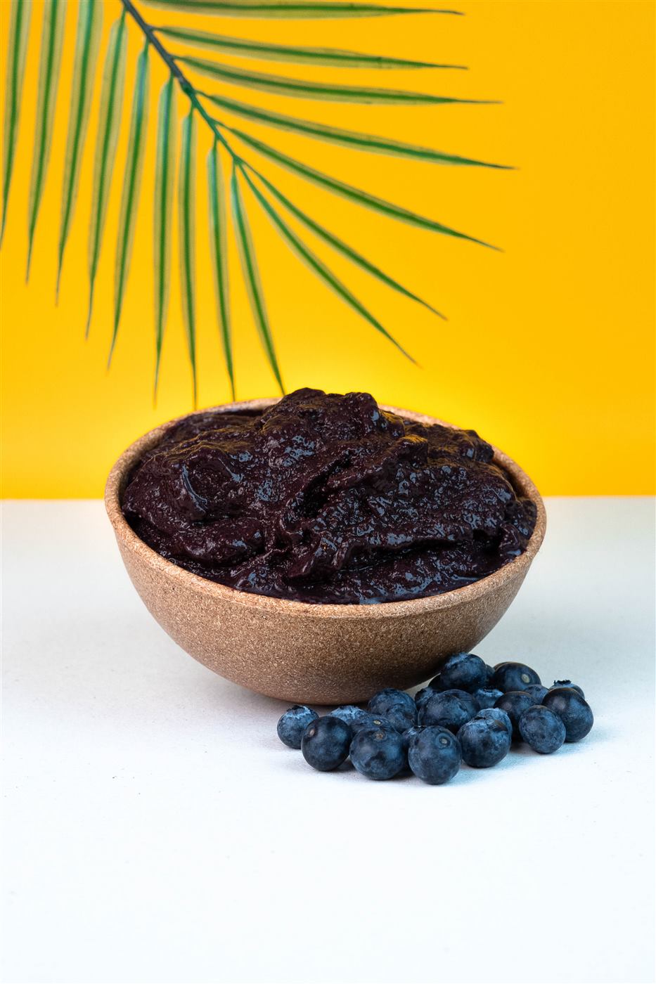 Açaí cremoso em tigela de fibra com folha de palmeira ao fundo
